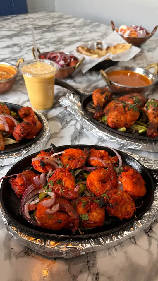 Tandoori Table in Cartersville showing review, garlic naan, tandoori shrimp, chicken tikka kebab, samosas, mango lassis, butter chicken, video by Downtown Cartersville on Facebook